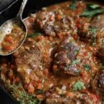 Cajun-Smothered Pork Medallions - Close-up shot in cast iron skillet with thyme sprigs