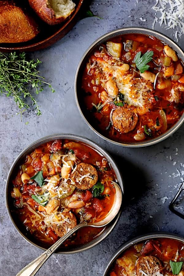 Photo of two bowls of Chorizo White Bean and Vegetable Soup on gray background.