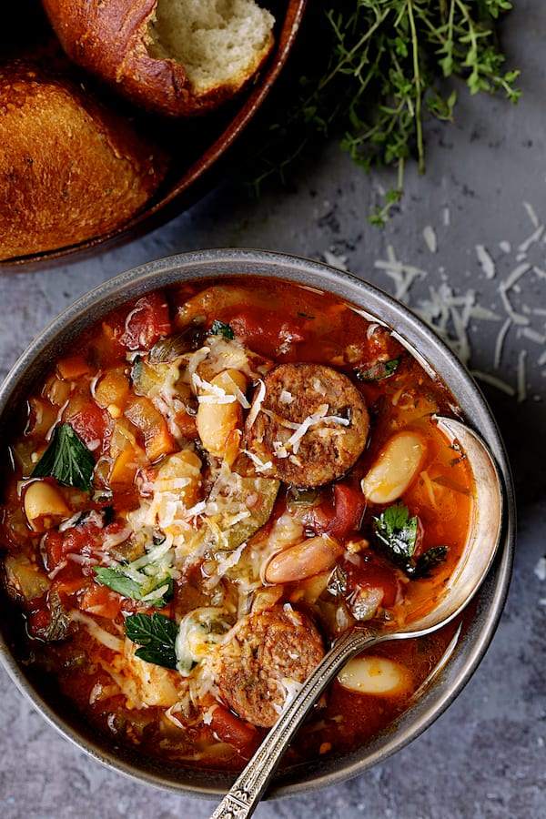 Close-up photo of one bowl of Chorizo White Bean and Vegetable Soup in gray bowl with soup spoon.