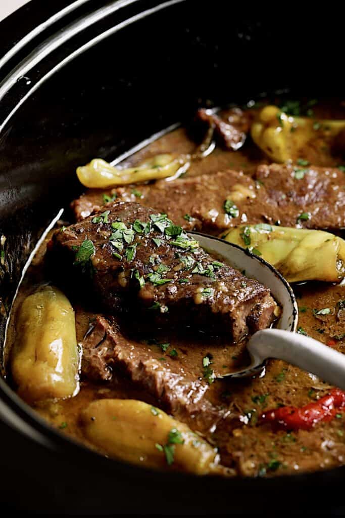 Close-up photo of Mississippi-Style Boneless Short Ribs Without Packaged Mixes being lifted out from slow cooker.