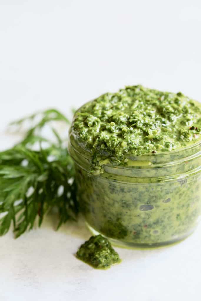 Photo of Carrot Top Salsa Verde in glass jar with some dripped on surface.