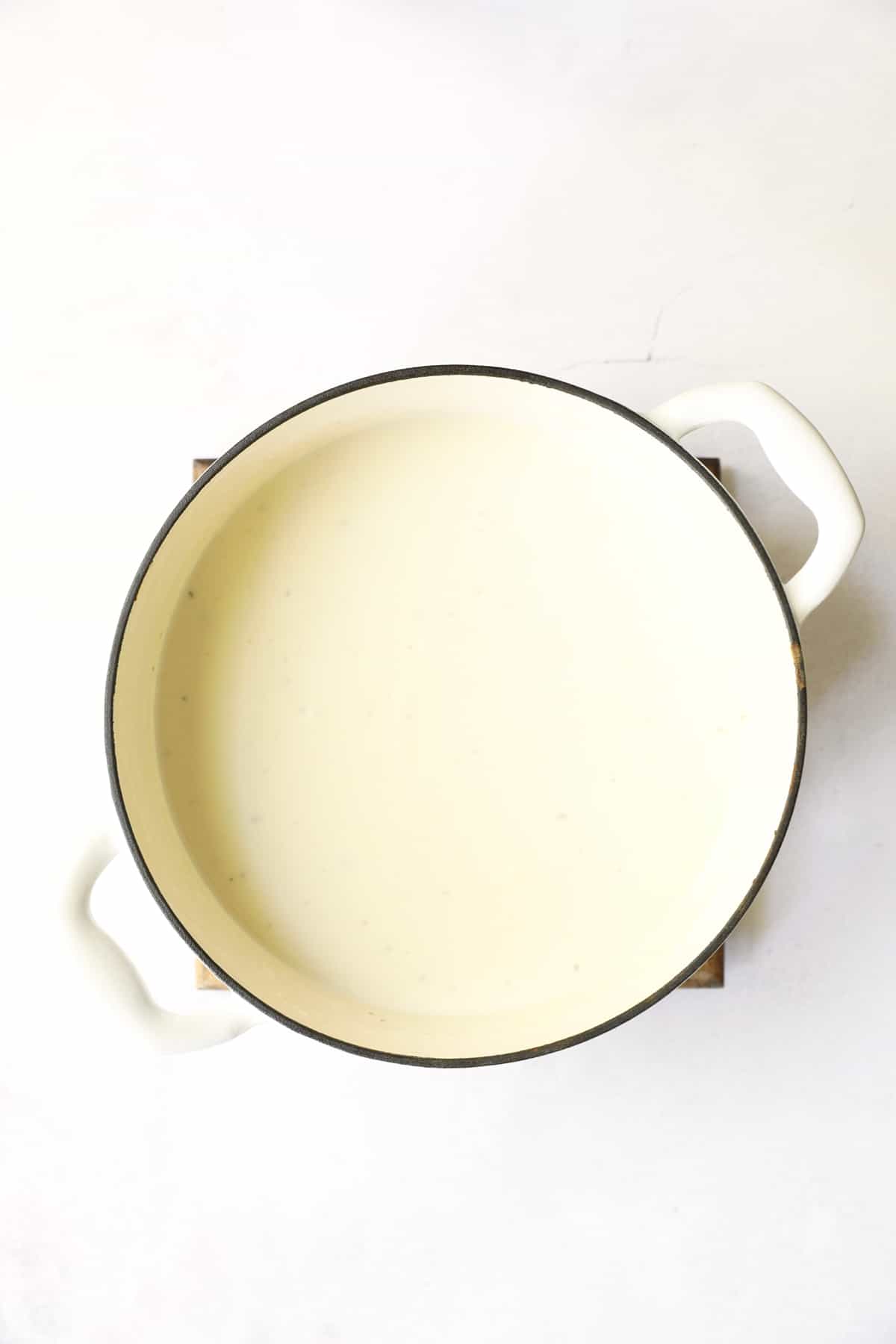 Photo of Potato Leek Soup with White Cheddar in white Dutch oven after being pureed.