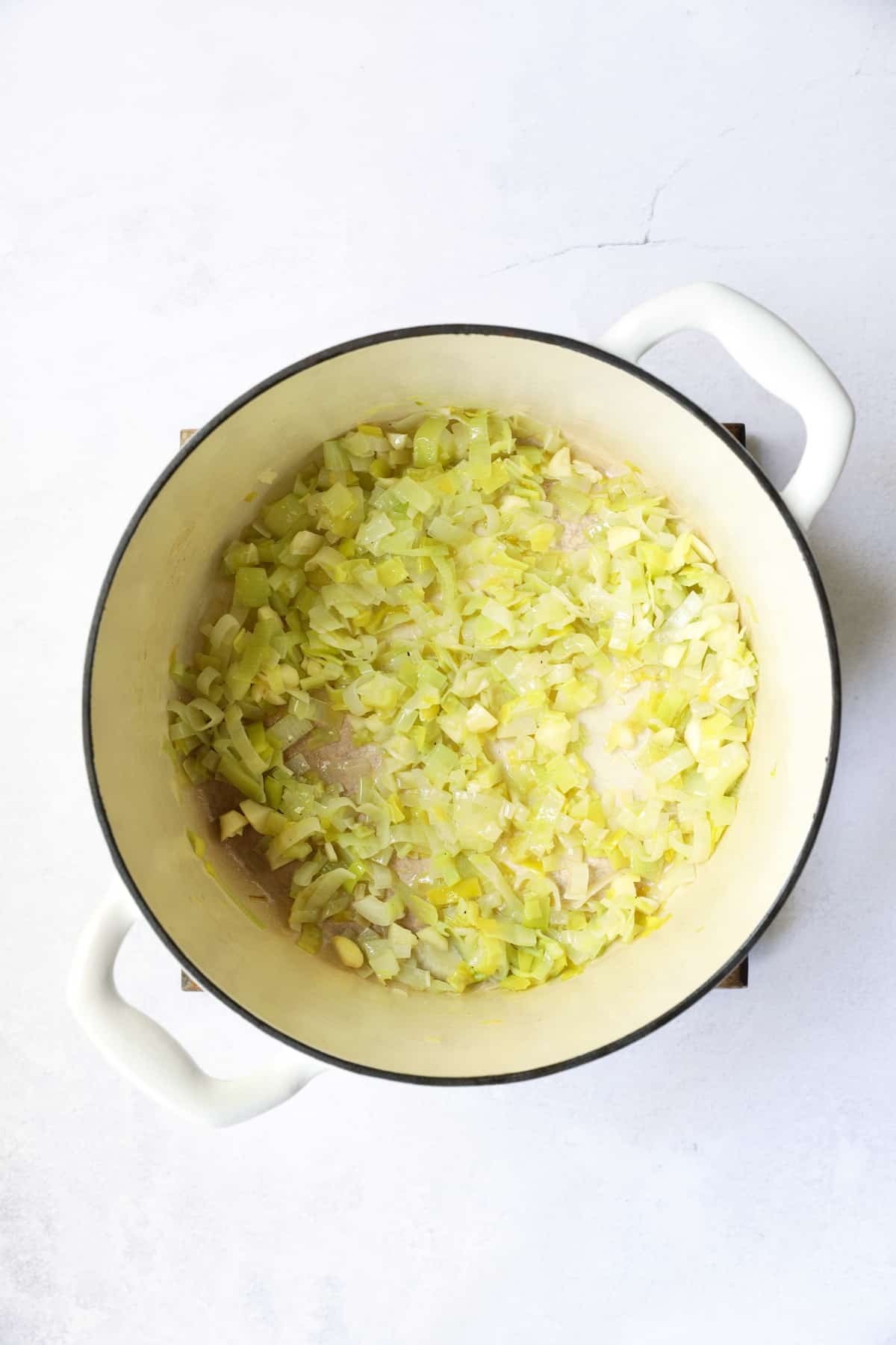 Photo of cooked leeks in white Dutch oven.