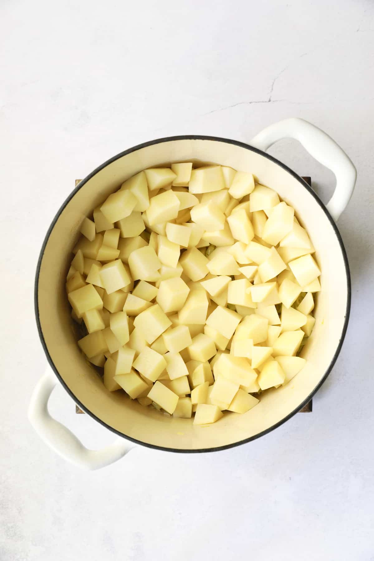 Photo of cubed potatoes in white Dutch oven.