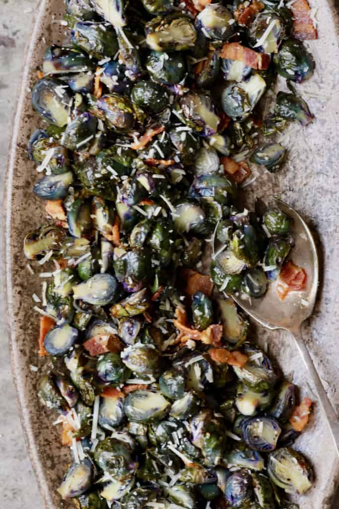 Close-up photo of Roasted Purple Brussels Sprouts with Bacon and Parmesan on brown platter.