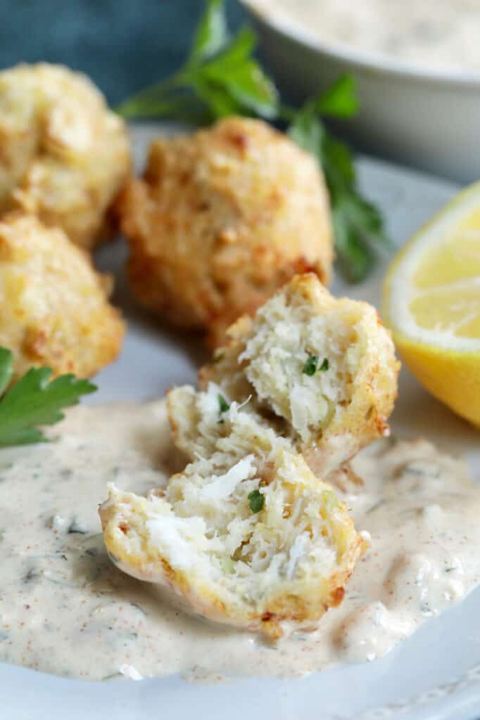 Close-up photo of a Crab and Artichoke Beignet with Jalapeno Remoulade showing interior of beignet on remoulade.