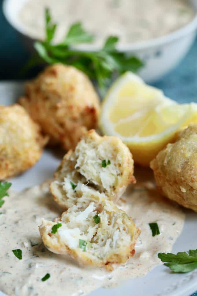 Close-up photo of Crab and Artichoke Beignets with Jalapeno Remoulade showing interior of beignet garnished with lemon and parsley.