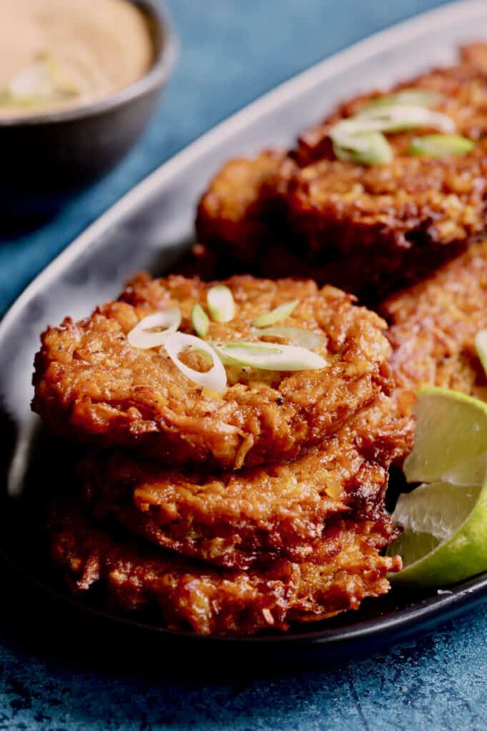 Photo of stack of three Korean Sweet Potato Latkes with Gochujang Mayonnaise with lime wedge.