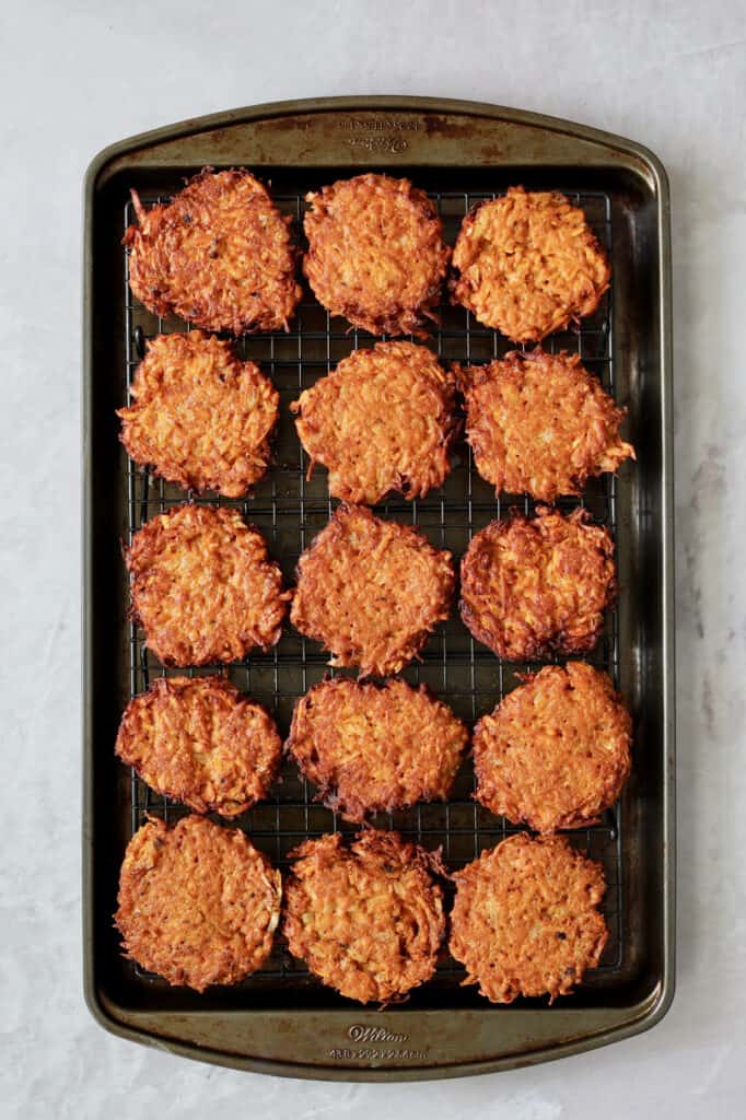 Photo of fried fritters set on rack over baking sheet.