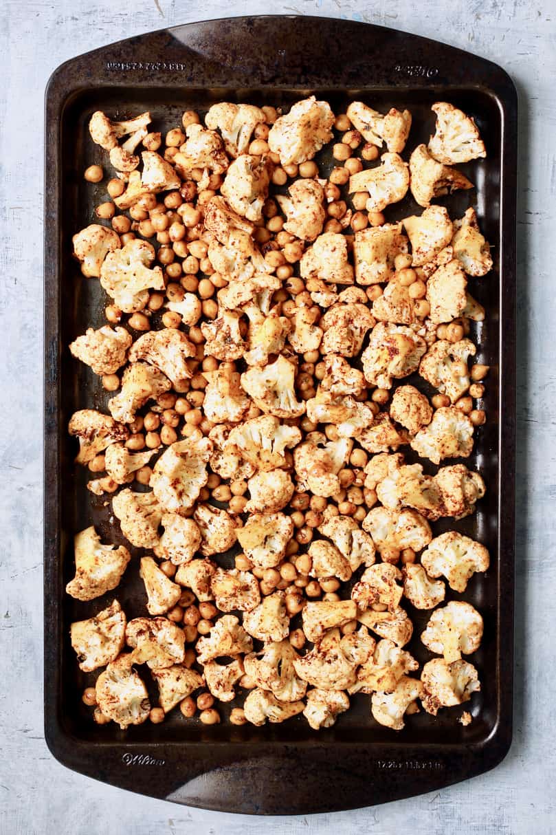 Photo of cauliflower and chickpeas on baking sheet before roasting.