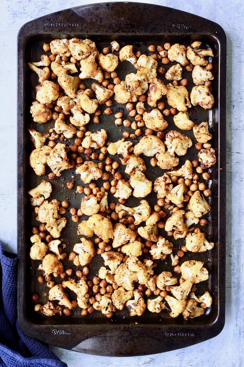 Photo of cauliflower and chickpeas on baking sheet after roasting.