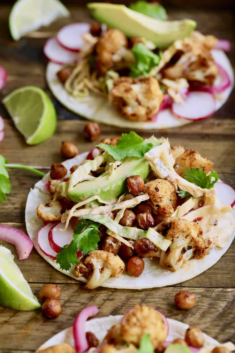 Close-up photo of Cauliflower and Chickpea Tacos with Chipotle Lime Slaw on wood surface.