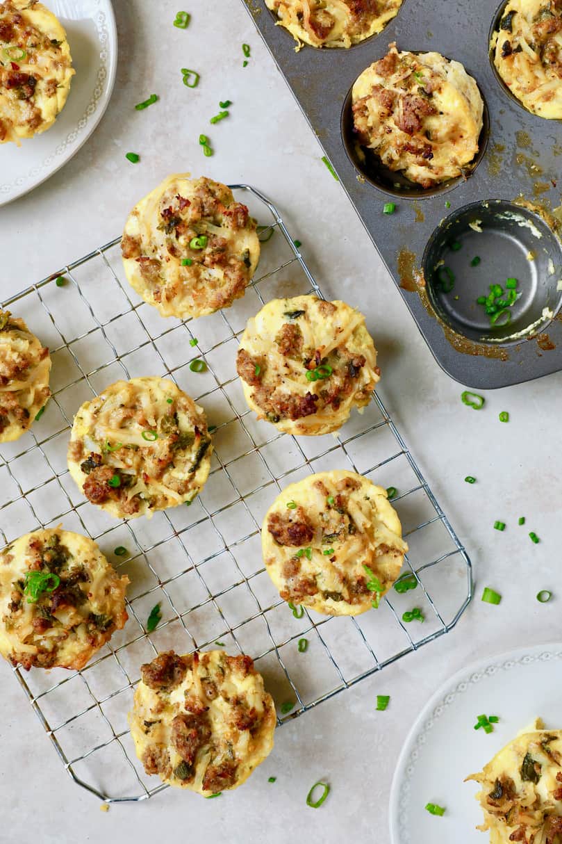Photo of Hash Brown Breakfast Muffins with Poblano Peppers and Gouda Cheese on cooling rack garnished with chives.