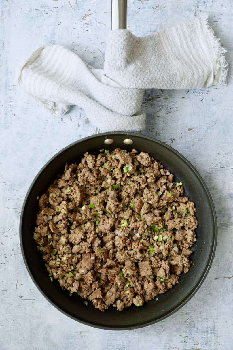 Photo of sausage and scallions cooked in skillet.