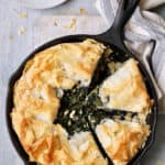 Skillet Spanakopita (Greek Spinach and Feta Pie) - Overhead shot in cast iron skillet with gray striped towel