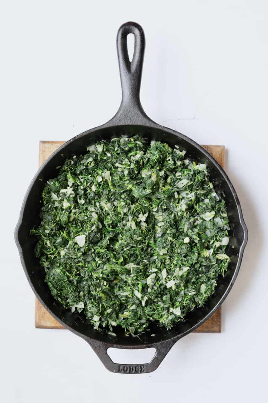 Photo of spinach and onions being cooked in cast iron skillet.