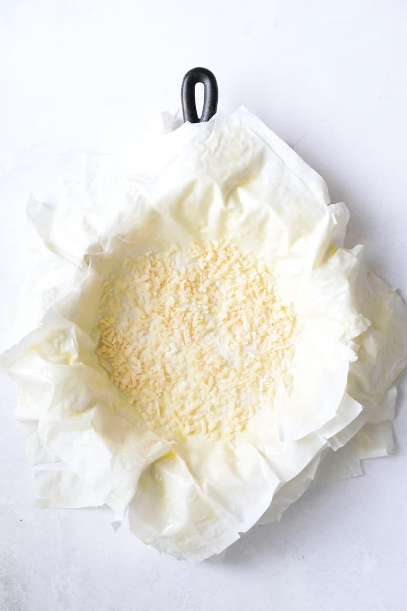 Photo of all the phyllo dough placed in the cast iron skillet covered with a layer of Parmesan cheese.