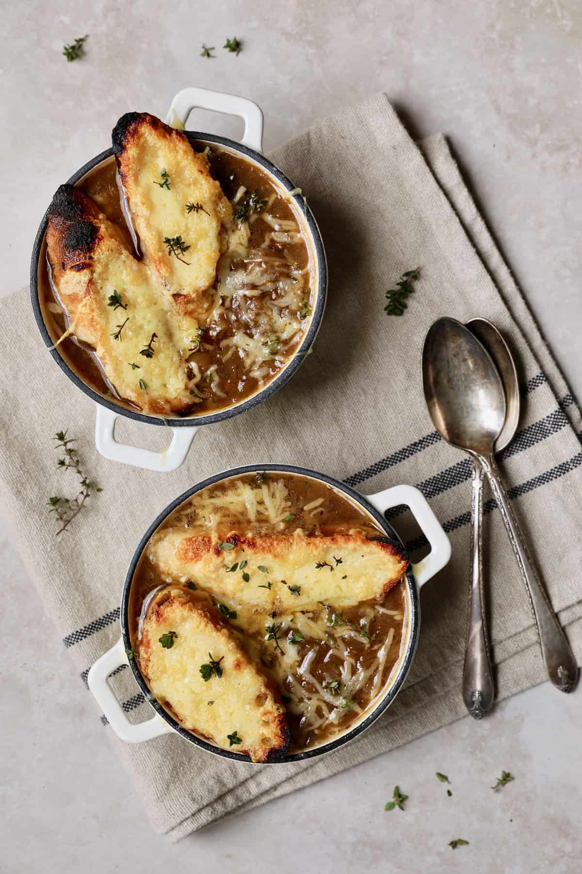 French Onion Soup for Two - Overhead hero shot of two bowls on beige background garnished with thyme