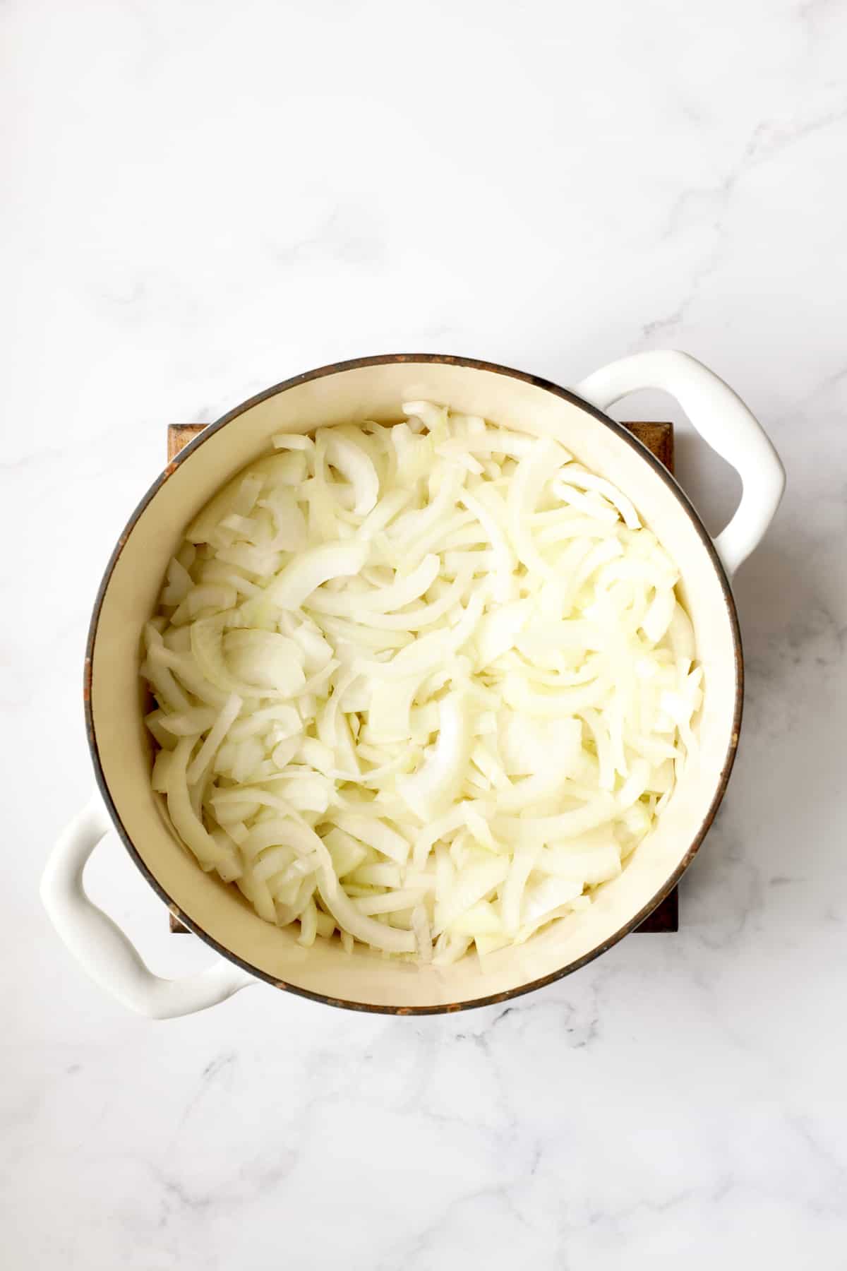 Overhead shot of onions in white Dutch oven