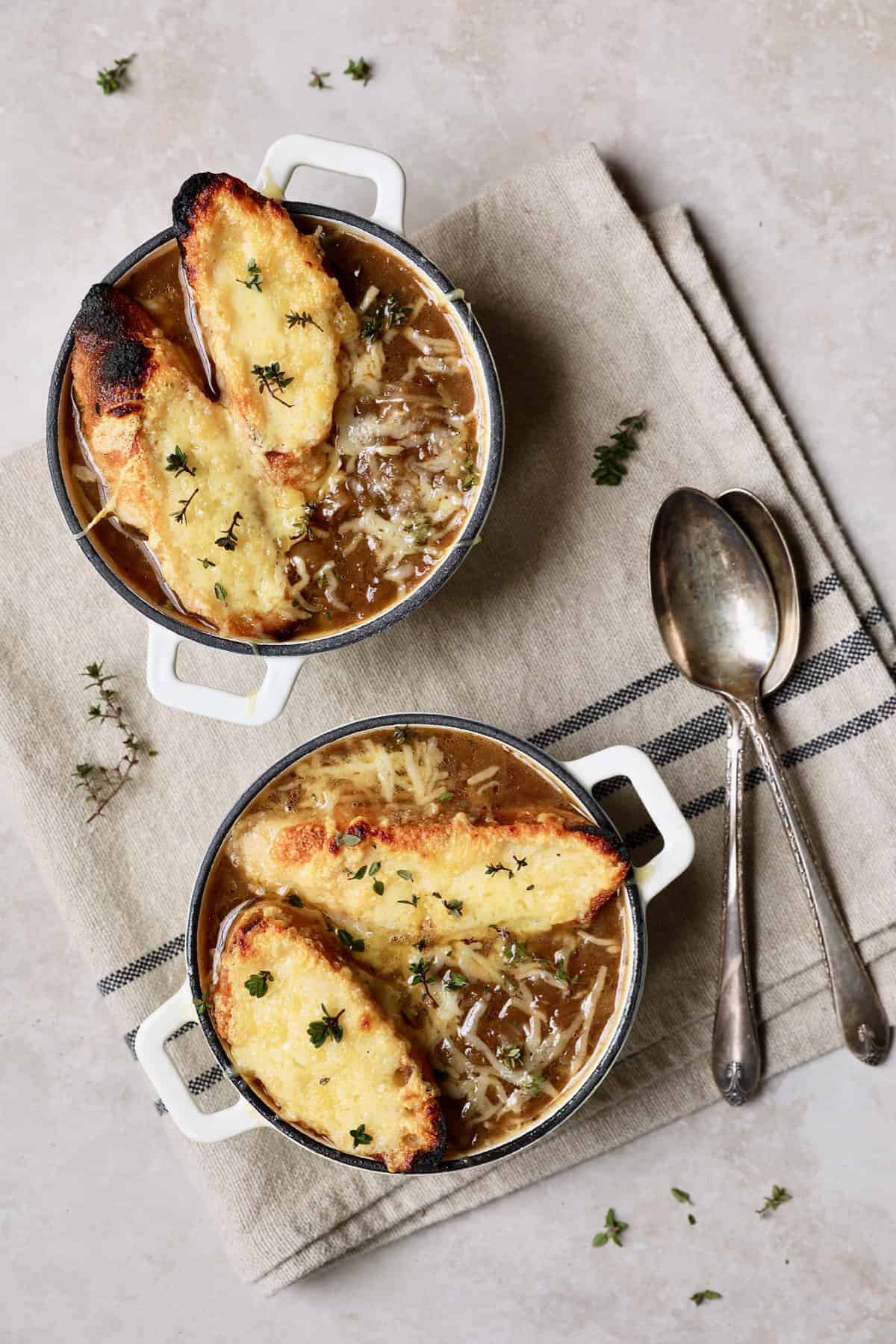 Photo of French Onion Soup with cheesy croutons on beige and black-striped napkin.