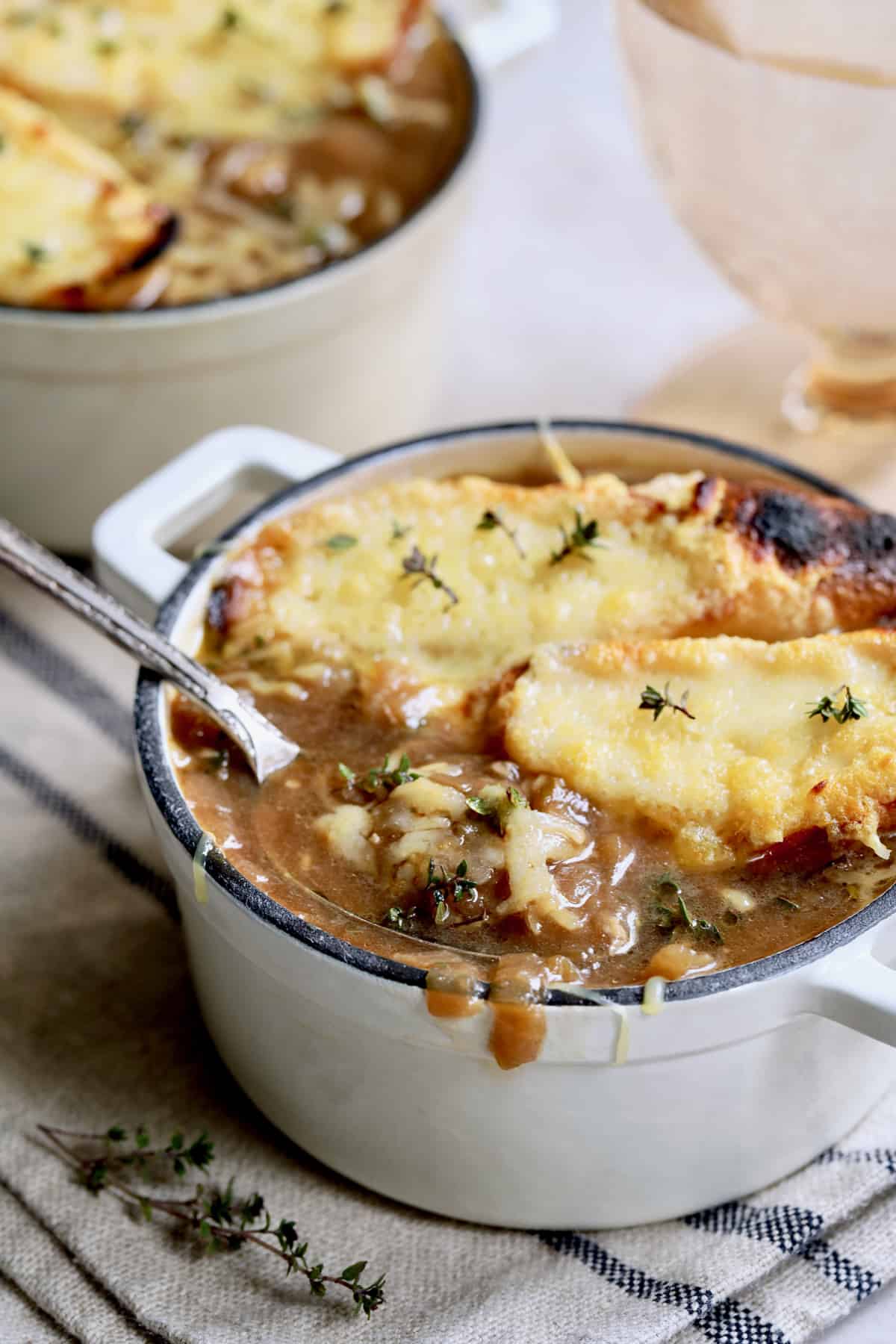 Photo of French Onion Soup for Two on black striped napkin with spoon lifting out some of the soup.