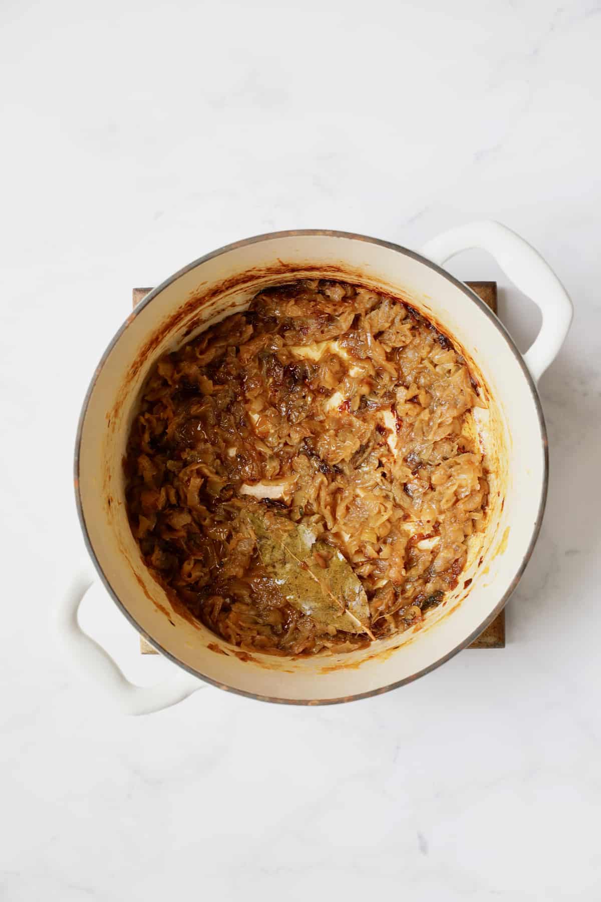 Overhead shot of caramelized onions in white Dutch oven