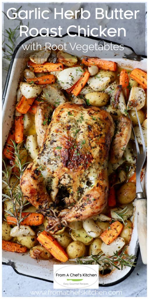 Garlic Herb Butter Roast Chicken with root vegetables in white roasting pan with meat fork.