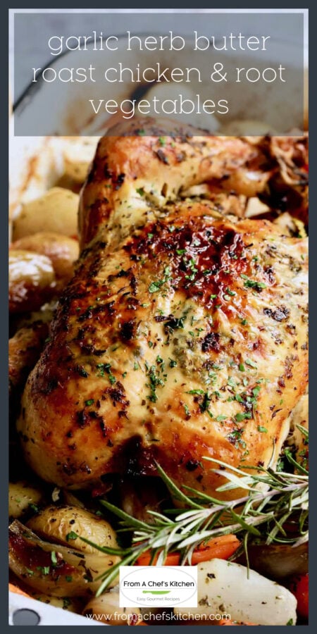 Garlic Herb Butter Roast Chicken with root vegetables in white roasting pan garnished with fresh rosemary.