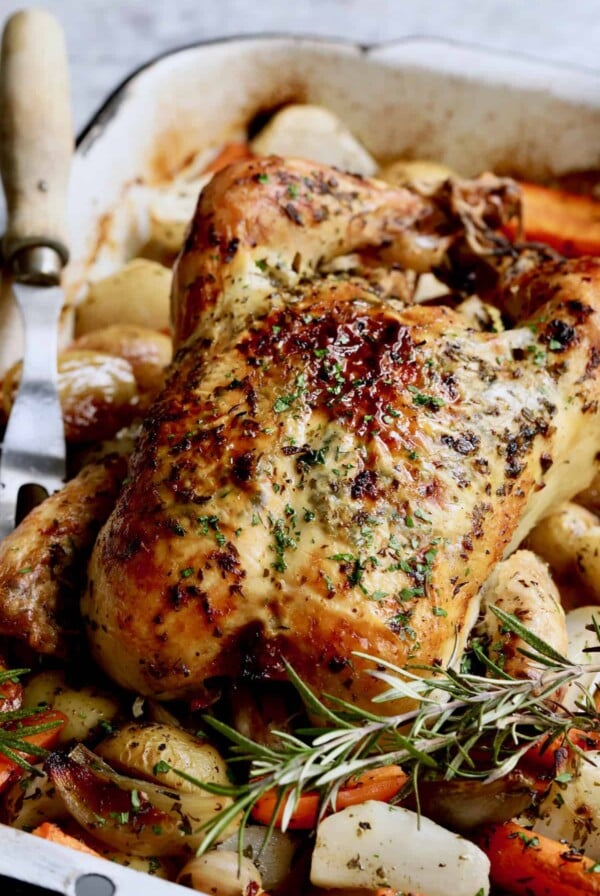 Photo of Garlic Herb Butter Roast Chicken with Root Vegetables with meat fork nearby.