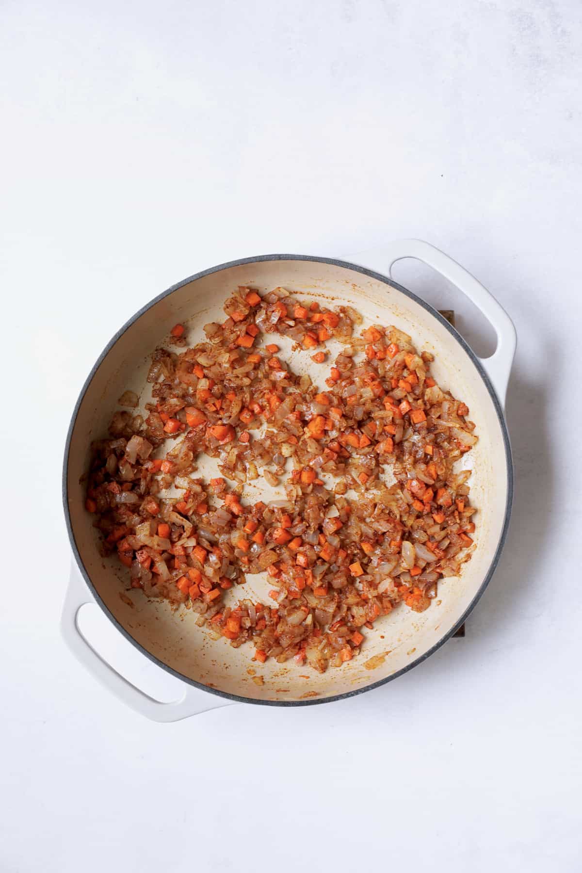 Photo of onions, carrots, garlic and paprika in white pan.