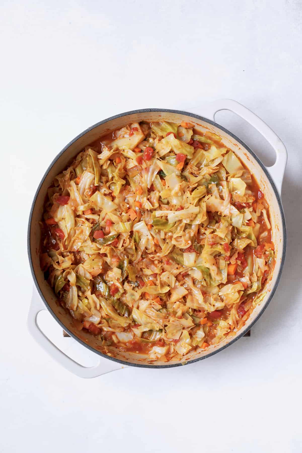 Photo of cooked cabbage in white cast iron pan.