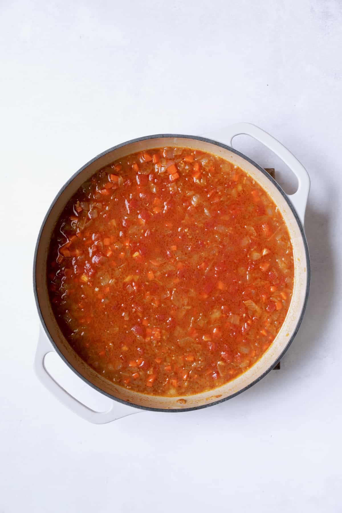 Photo of stewed cabbage with tomatoes added to pan.