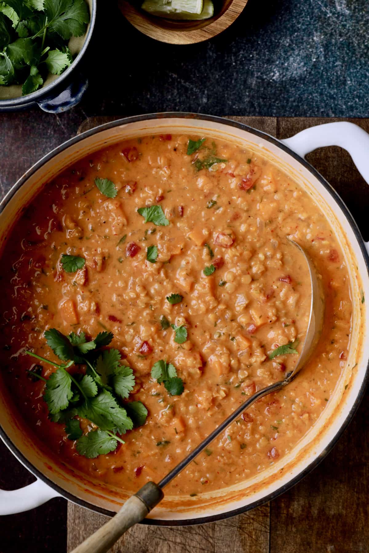 Photo of Thai Red Curry Sweet Potato and Lentil Soup in white Dutch oven with soup ladle.