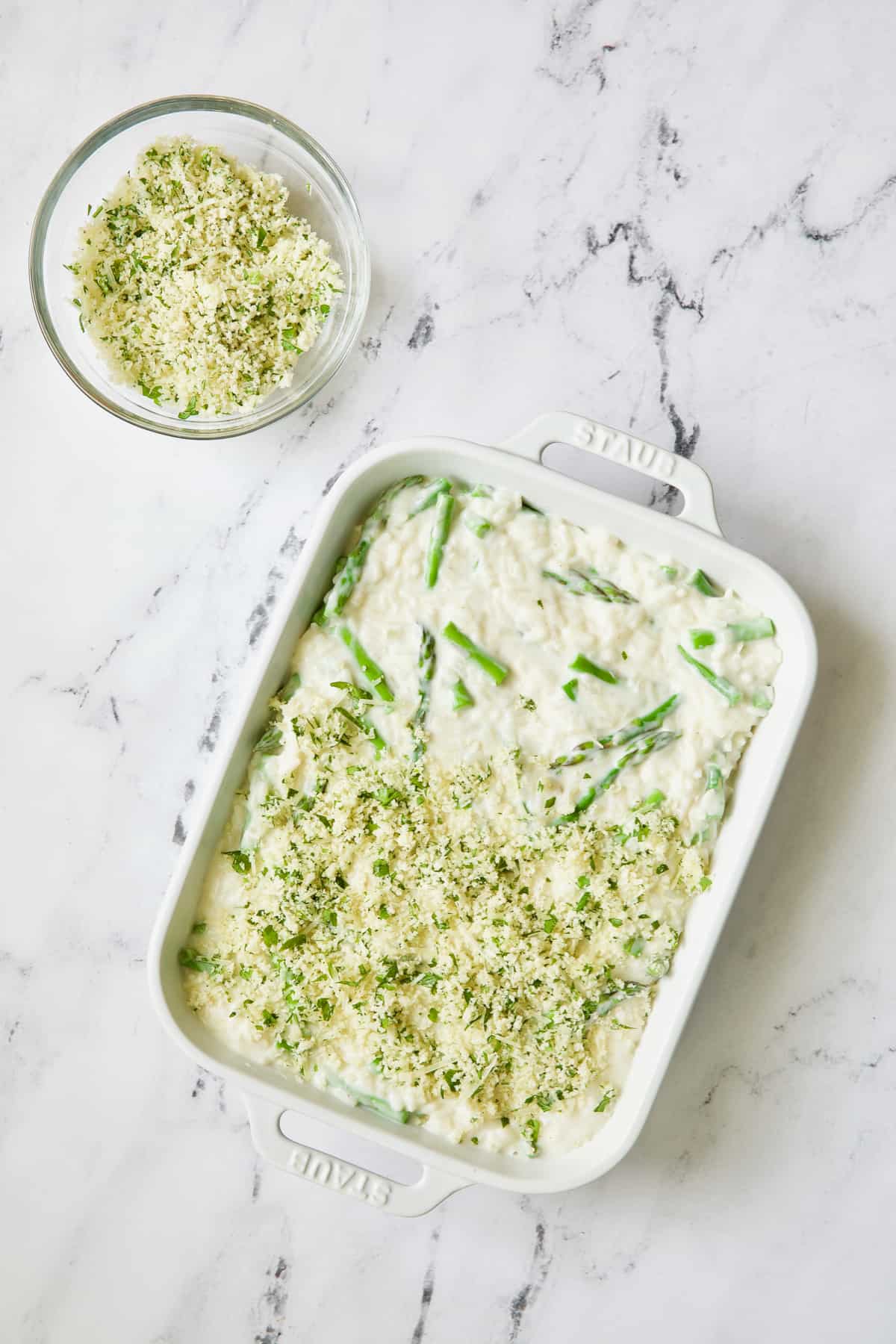 Photo of asparagus casserole as breadcrumb topping is being applied.
