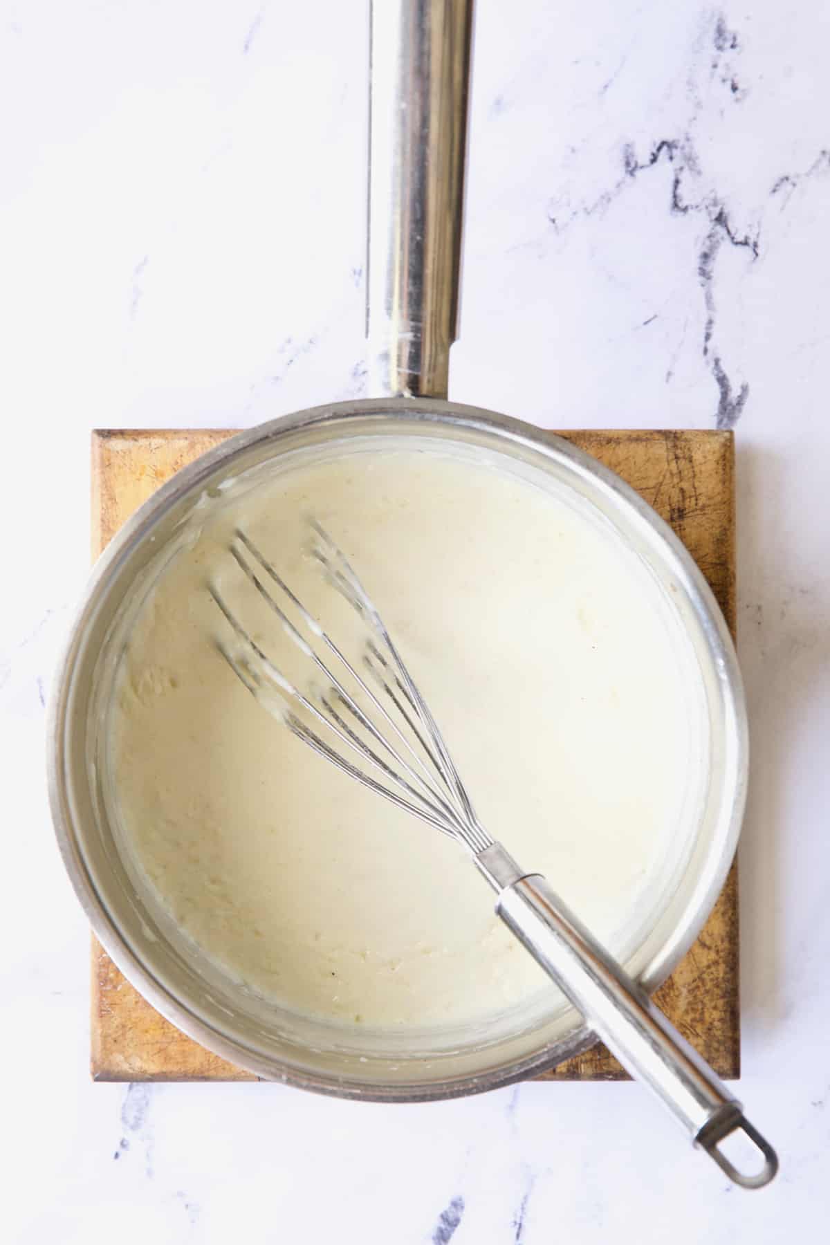 Photo of cream sauce in stainless steel saucepan.