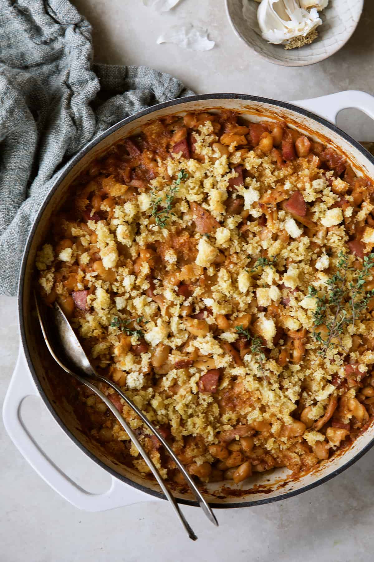 Photo of Easy Weeknight Chicken and Sausage Cassoulet with gray napkin and serving utensils.