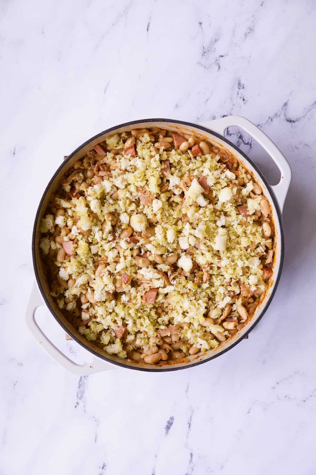 Photo of Easy Weeknight Chicken and Sausage Cassoulet in white cast iron skillet before baking.