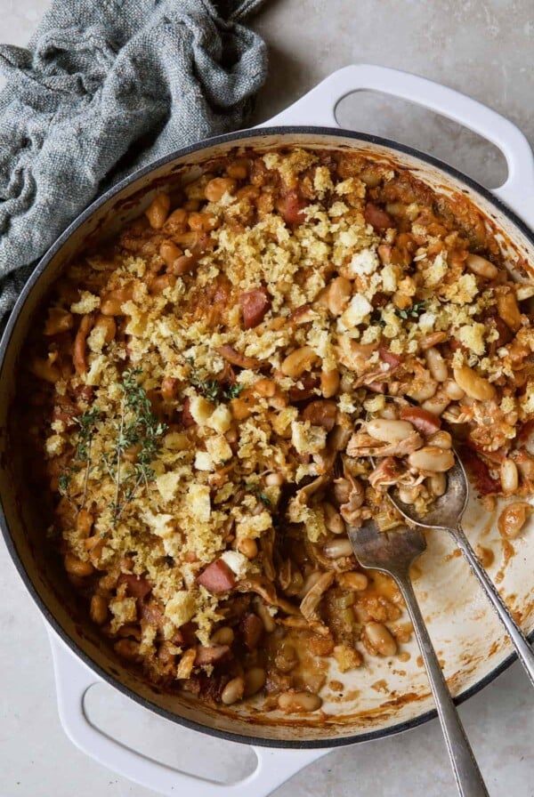 Photo of Easy Weeknight Chicken and Sausage Cassoulet after some has been served with serving utensils.