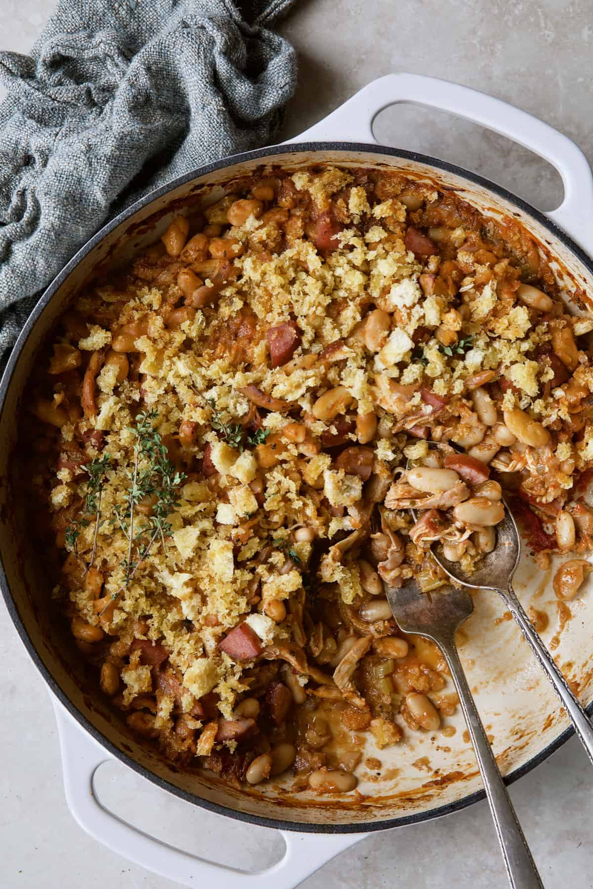 Photo of Easy Weeknight Chicken and Sausage Cassoulet after some has been served with serving utensils.
