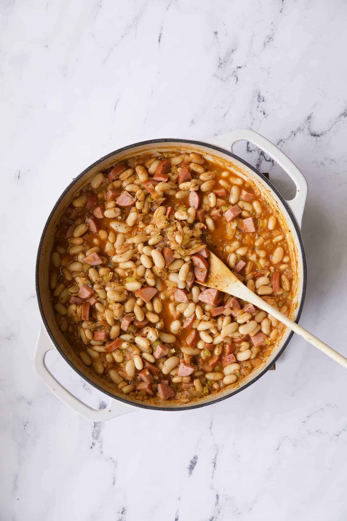 Photo of cassoulet after beans and sausage have been added.