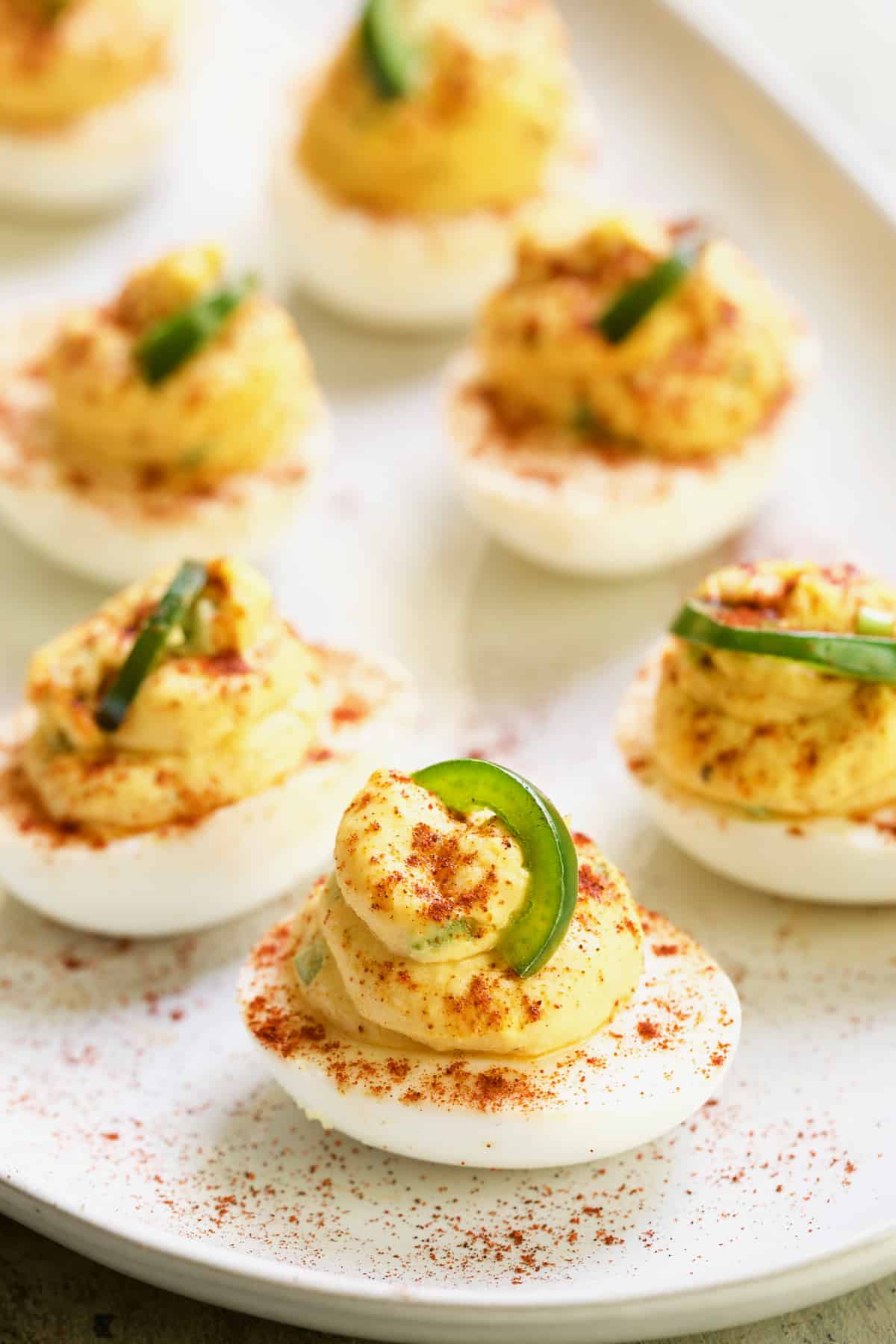 Photo of Jalapeno Pimento Cheese Deviled Eggs on white platter.