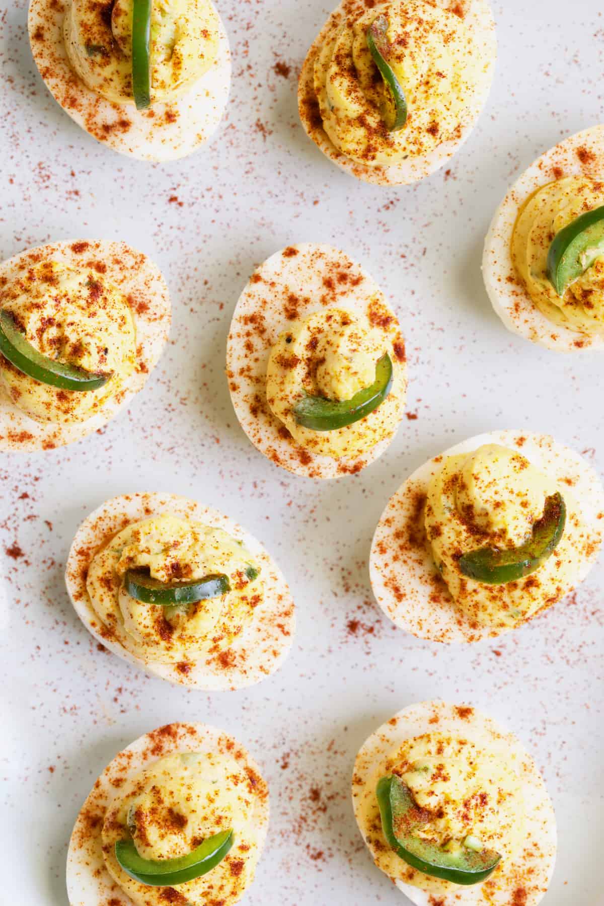 Photo of Jalapeno Pimento Cheese Deviled Eggs garnished with jalapeno and paprika.