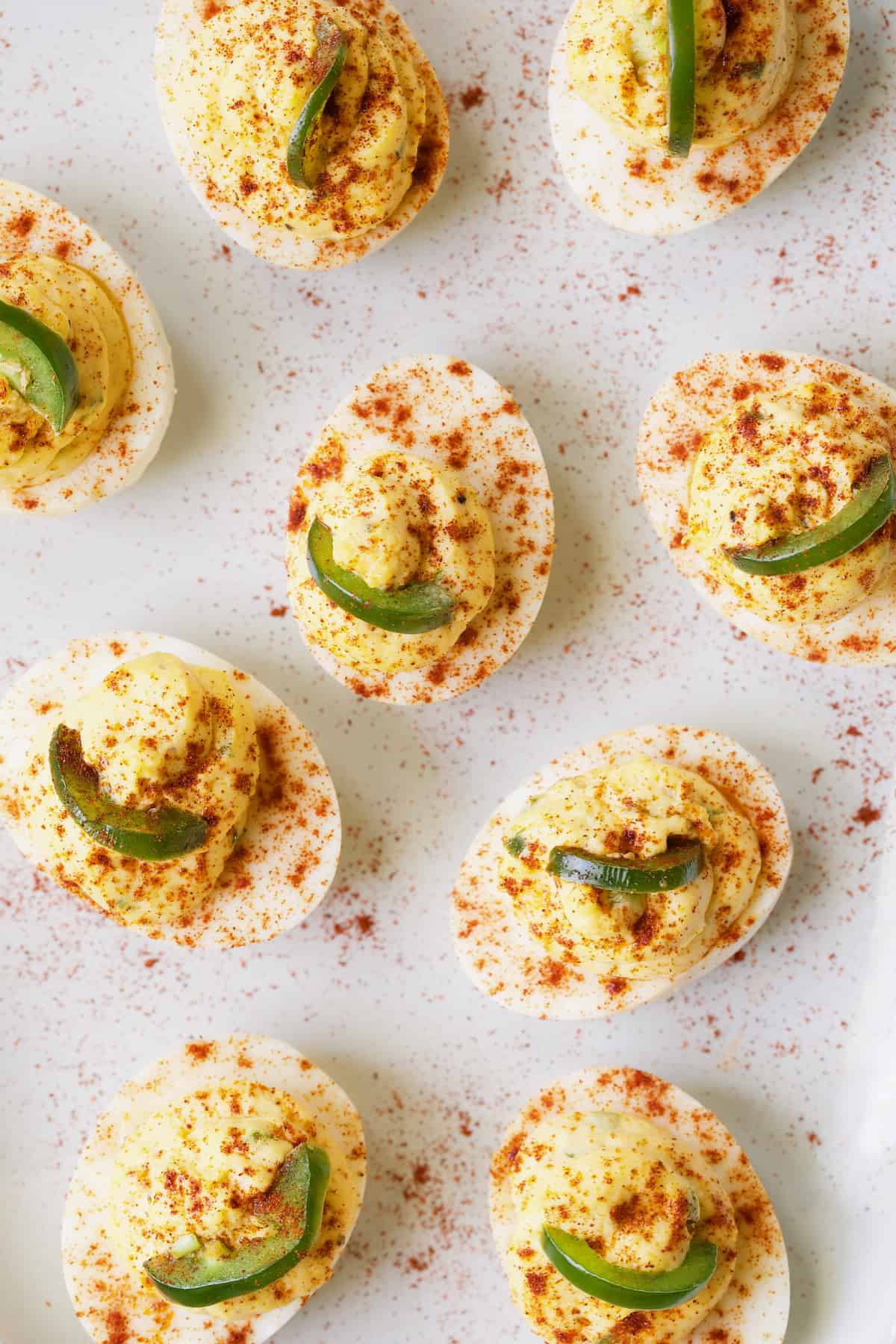 Photo of Jalapeno Pimento Cheese Deviled Eggs garnished with jalapeno slices and paprika.