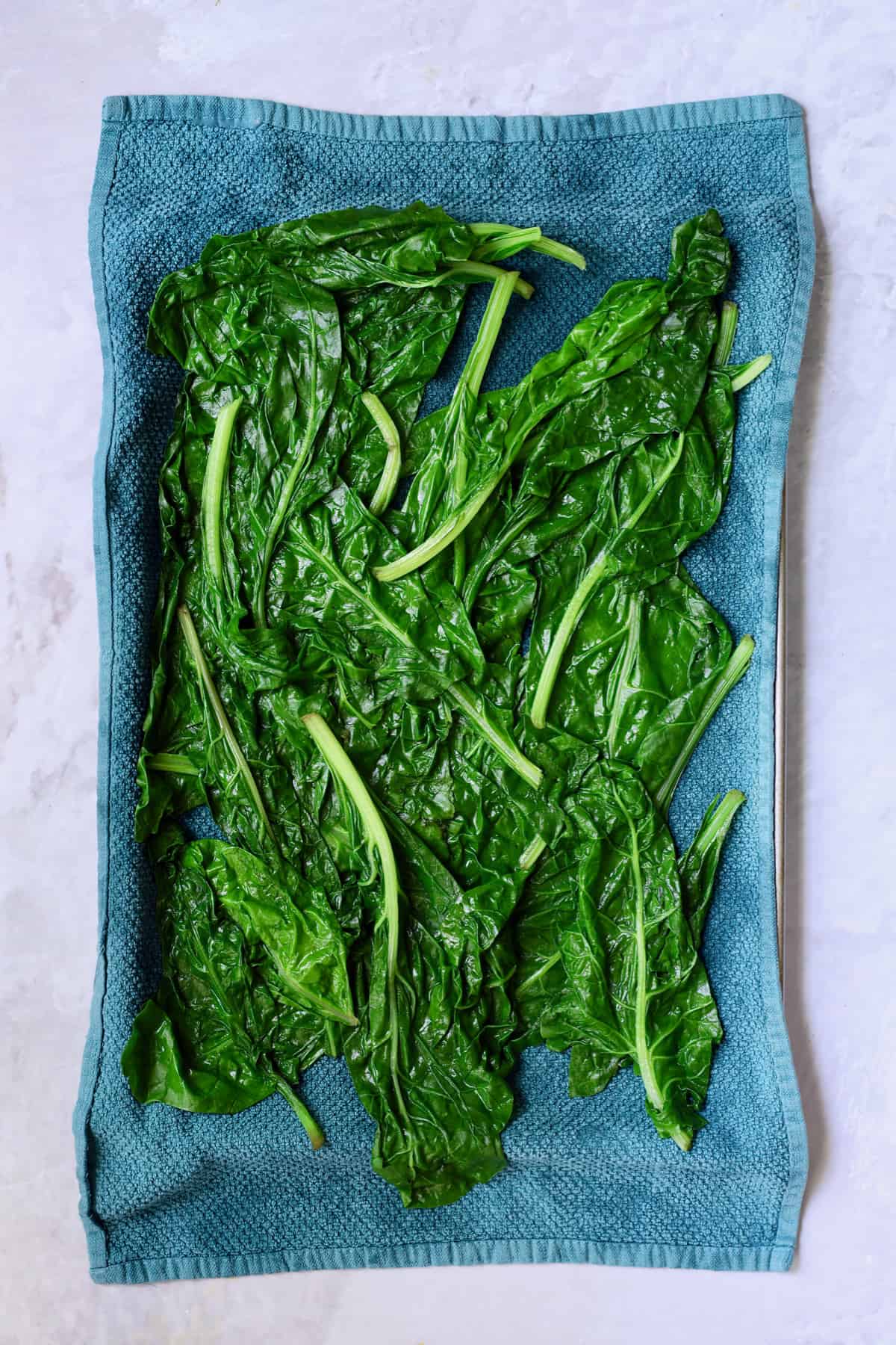 Photo of blanched Swiss chard leaves on blue towel.