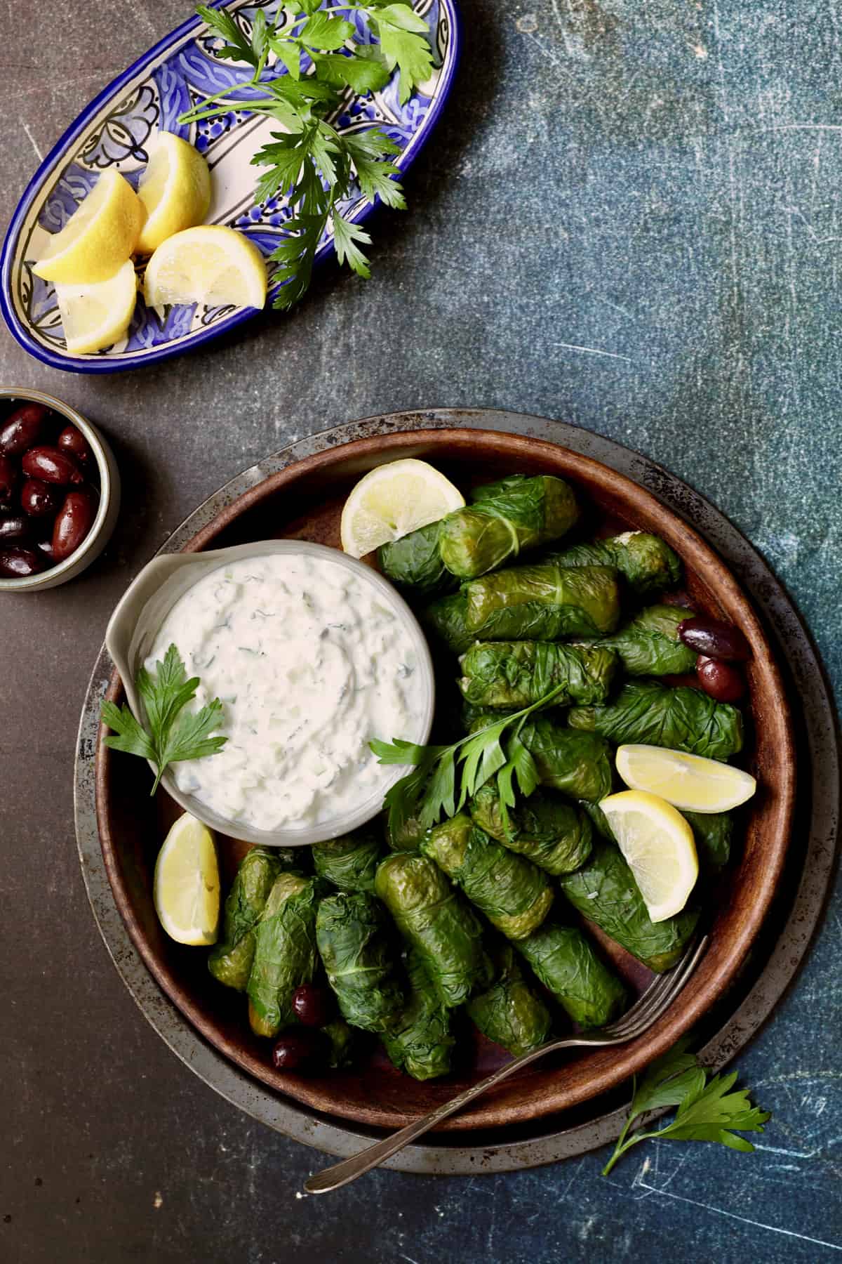 Photo of Swiss Chard and Quinoa Dolmas with Tzatziki with lemon wedges and parsley sprigs.