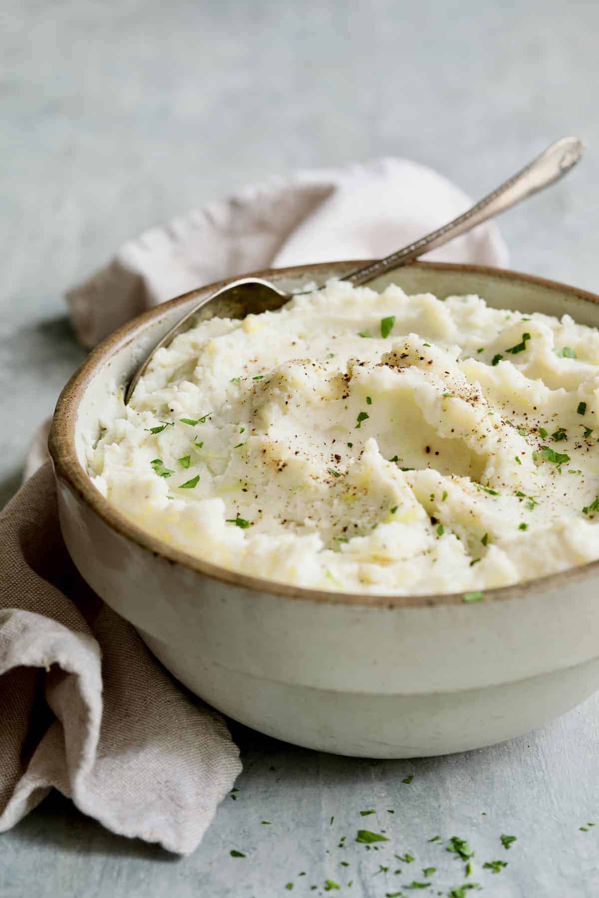 Photo of colcannon in stoneware bowl with serving spoon garnished with fresh parsley.