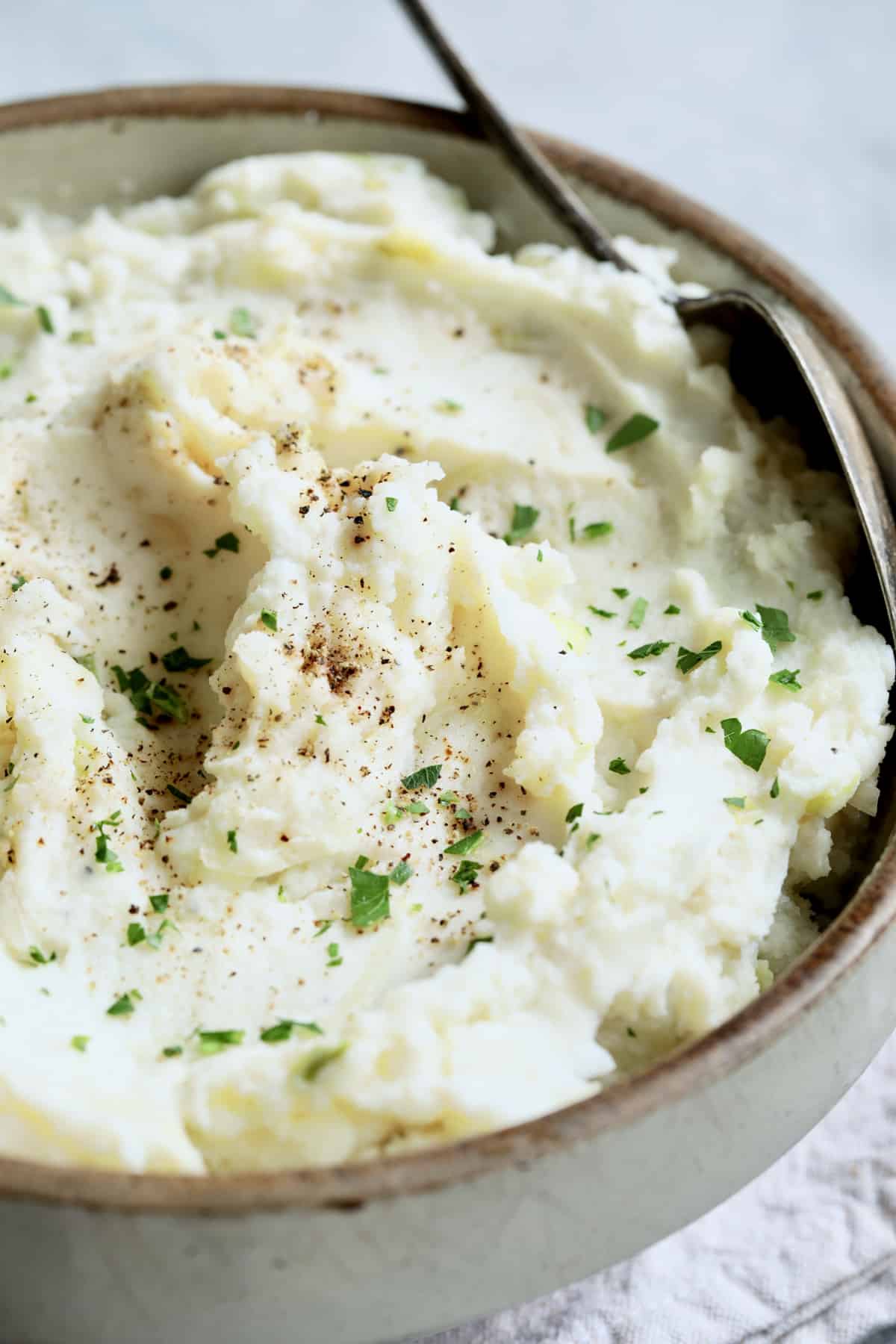 Close-up photo of colcannon in stoneware bowl garnished with fresh parsley.