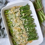 Photo of Asparagus Cordon Bleu in white rectangular baking dish on blue background.