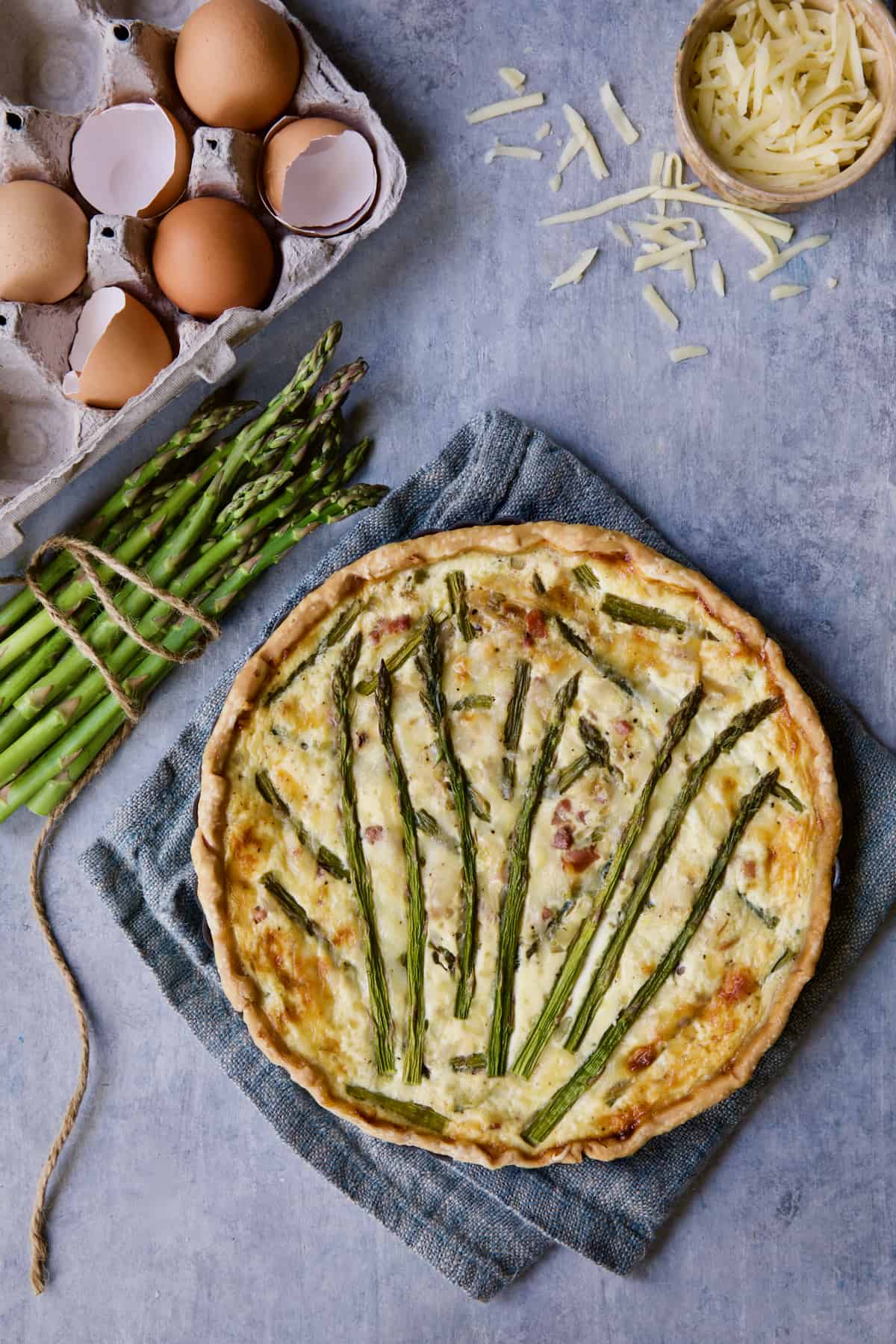 Photo of Asparagus Prosciutto and Fontina Tart with eggs, asparagus and cheese scattered about.
