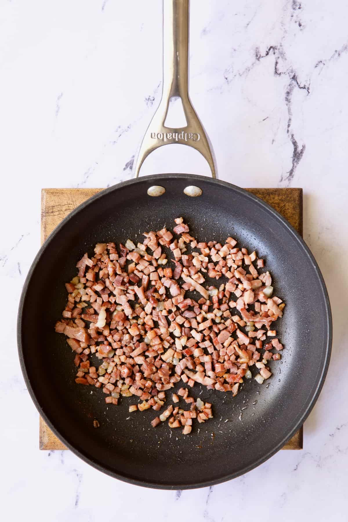 Photo of diced prosciutto being cooked in nonstick skillet.
